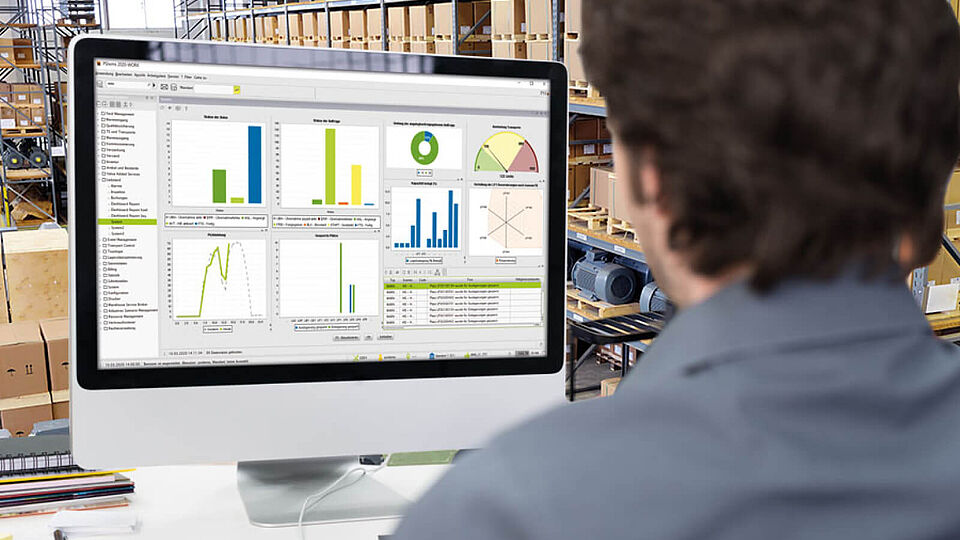 Blick über die Schulter eines Mitarbeiters im Lager auf den Monitor, auf dem die Software PSIwms zu sehen ist.