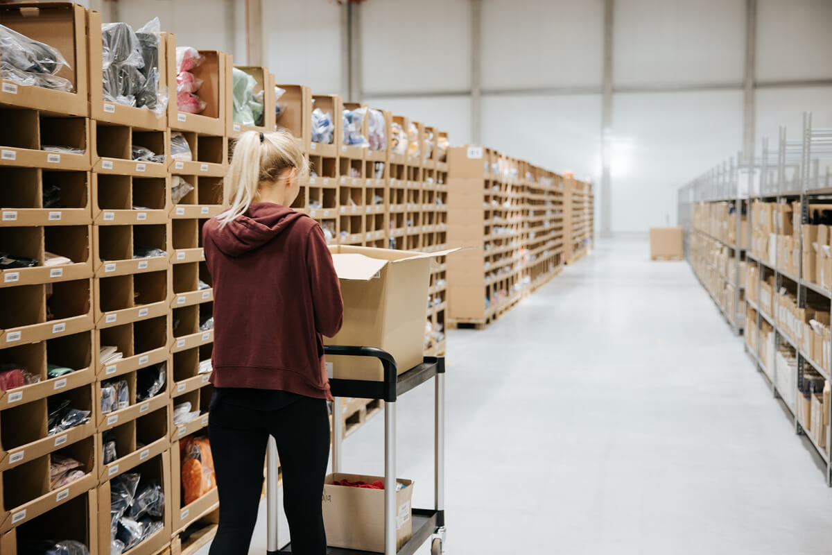 An employee moves a trolley with parcels through the aisle in the warehouse